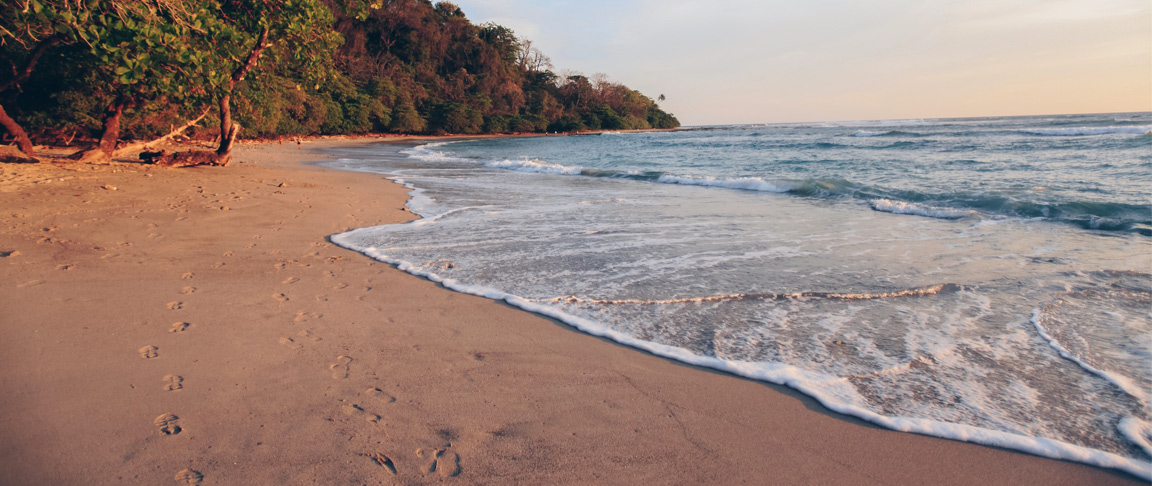 Stunning sunset over the Pacific Ocean at Beach Break Santa Teresa, Costa Rica, with vibrant hues of orange and pink reflecting on the calm waters